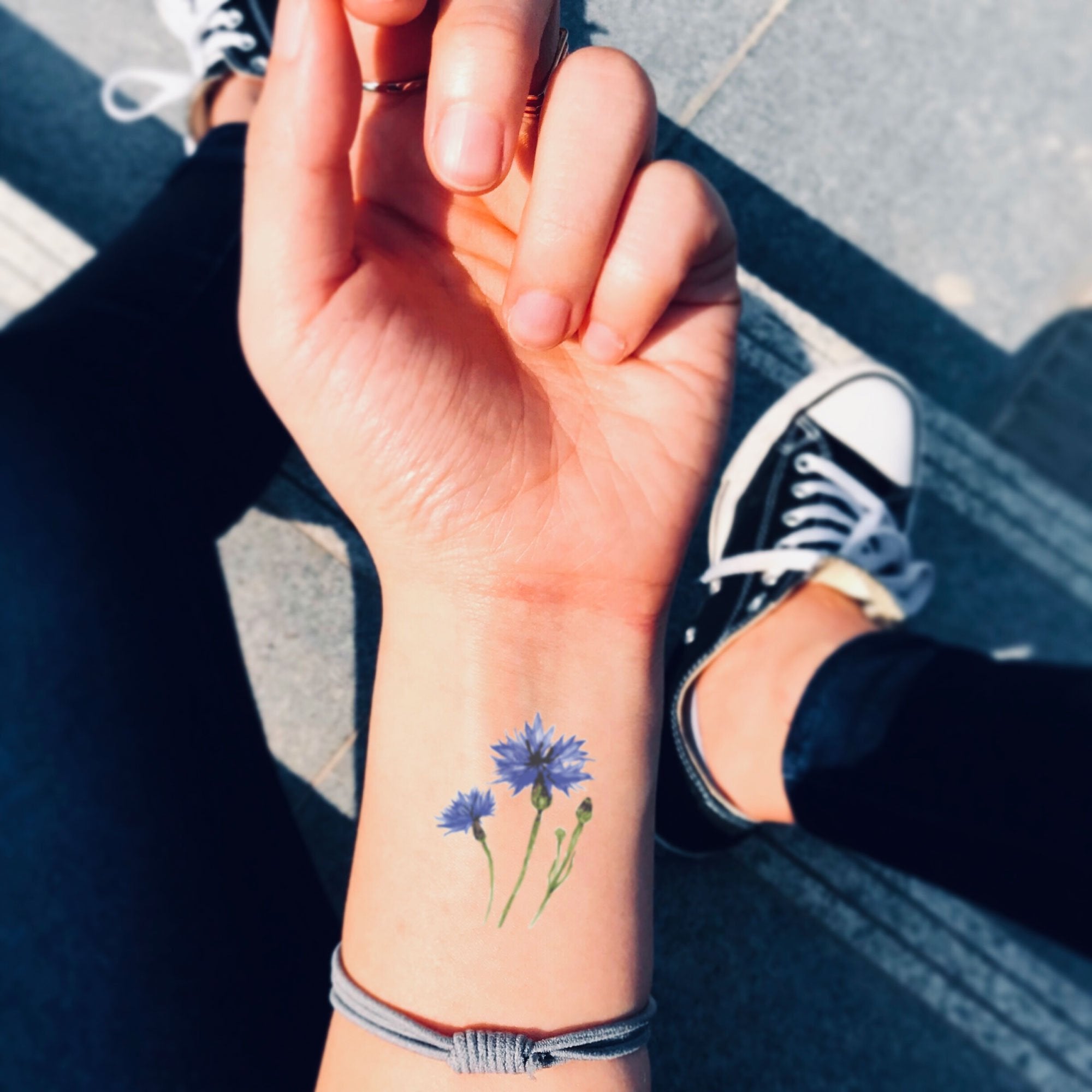 Fine line flower tattoos on the left wrist.